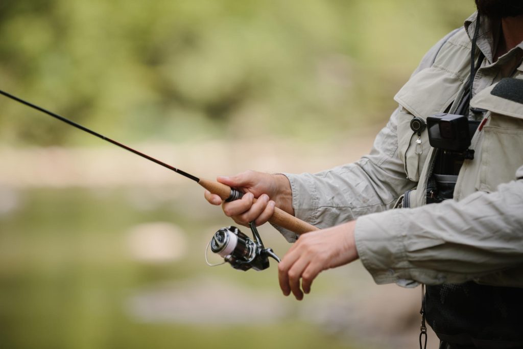 Fisherman holding fishing rod, enjoying trout fishing in nature